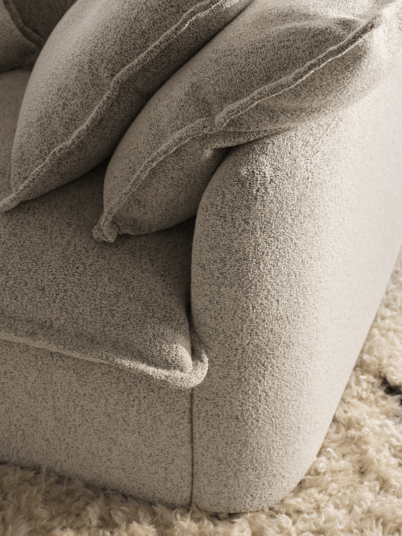 Close-up of cream boucle Koala sofa fabric texture with plush back cushions on shaggy rug