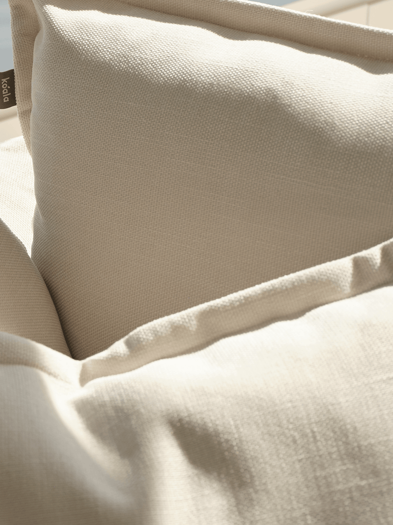Close-up of cream linen Koala sofa fabric detail with Koala brand tag on cushion
